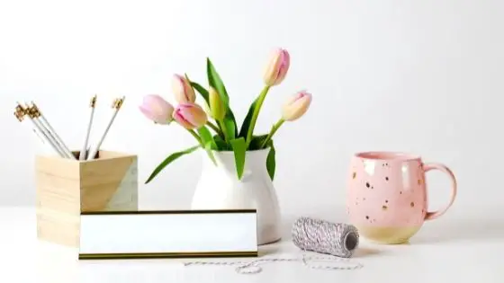 Pink mug next to pink tulips and pencils