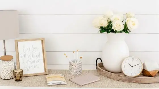 Table with white flowers, clock, stationery and lamp
