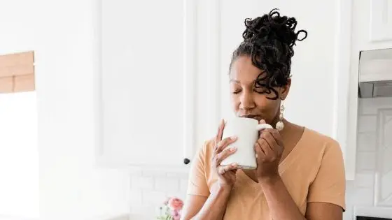 African-American woman standing in kitchen holding a cup of coffee