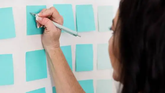 Woman writing on blue post-it notes