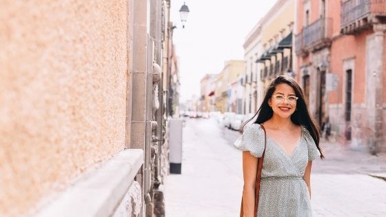 Girl wearing glasses walking in the streets smiling