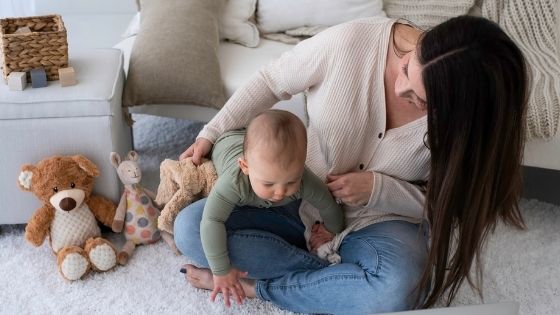 Mom sitting on the floor playing with baby and his toys