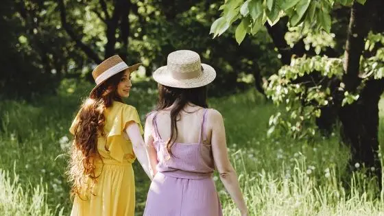 Two Caucasian girls holding hands walking in the woods