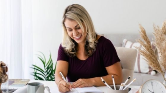 Woman smiling sitting at her desk and writing