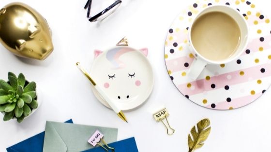 Table with cup of coffee, envelopes, flowers, stationery and a piggy bank