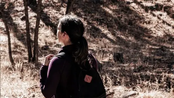 Girl carrying backpack and preparing to go on a hike