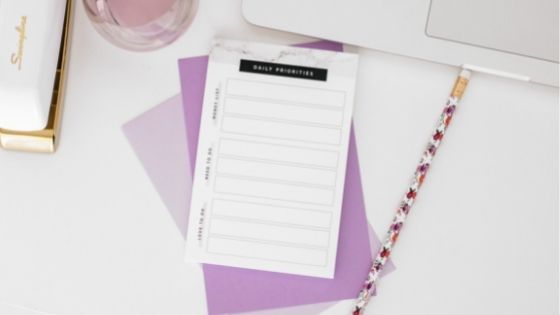Stationery on a desk and a paper written Daily Priorities