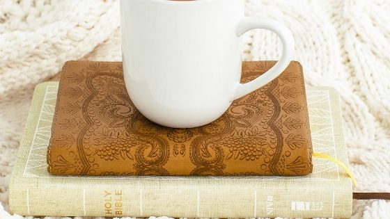 Cup of coffee on top of Bible and Brown Journal