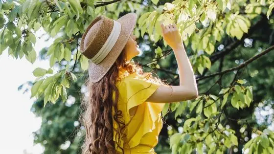 Caucasian girl in the woods looking up at a tree during summer