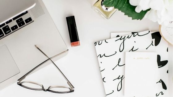 Laptop, glasses, notebook and flowers on a table