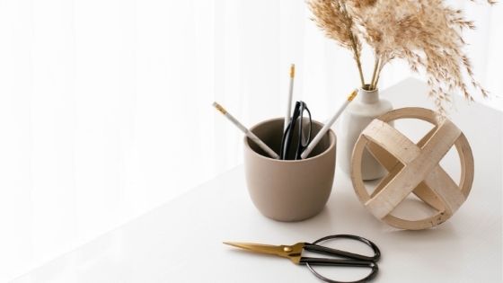 Scissors next to cup with stationery and vase
