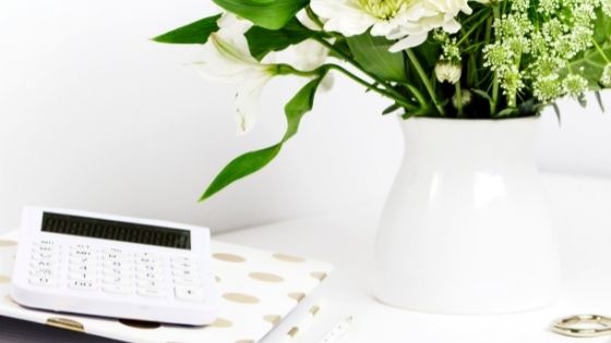 Vase with flowers, next to notebook and calculator on a desk
