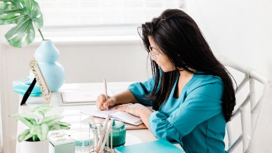 Caucasian woman sitting at her desk and writing in her notebook