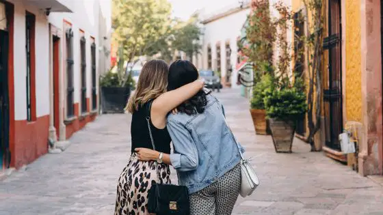Two women hugging while walking in the street