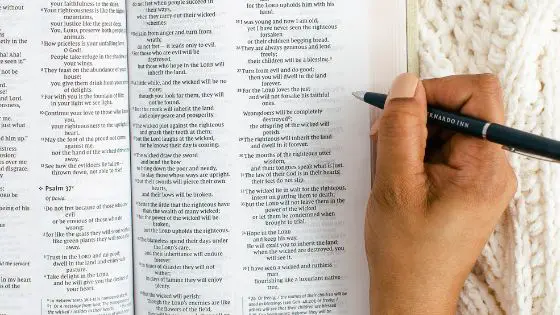 Woman holding pen and about on write in an open Bible