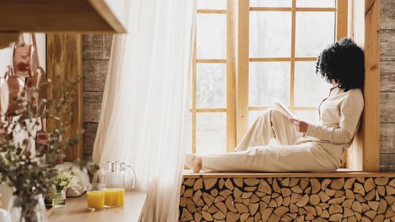 Woman sitting by the window writing in her notebook in the morning