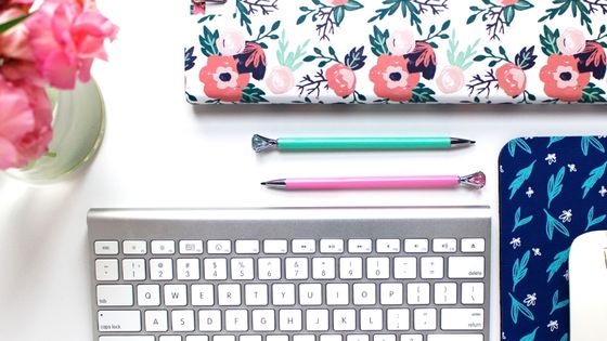 Desk with flowers, notebook, stationery and computer