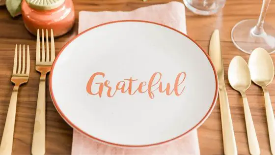 Plate written grateful on a table with cutlery next to it