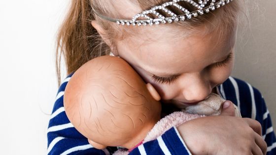 Caucasian girl with a crown holding her doll