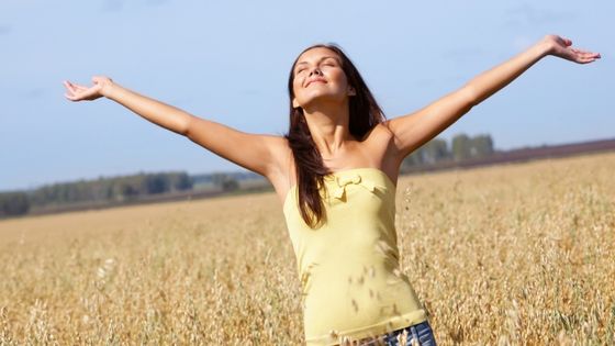 Caucasian woman with eyes closed, hands raised surrendering to God