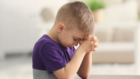 Young boy sitting with head bowed and praying